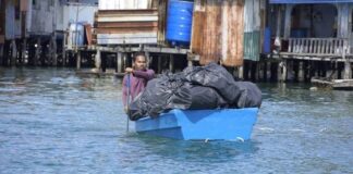 Penduduk dayung perahu penuh sampah ke tempat pelupusan